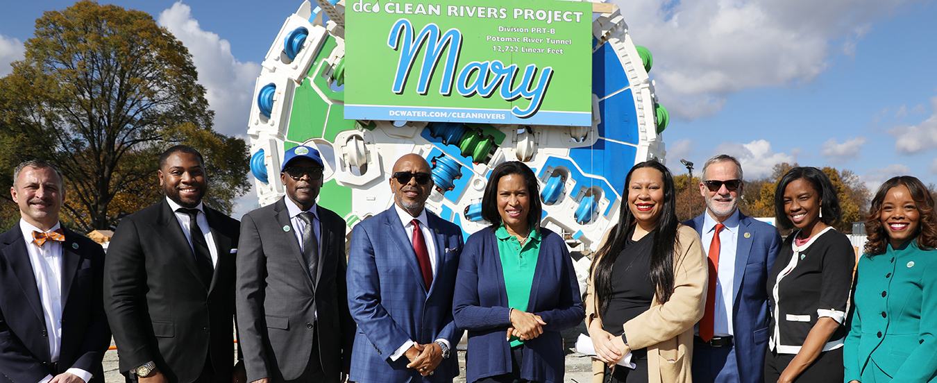 Mayor Bowser and other dignitaries pose for a photo in front of Mary the tunnel boring machine.